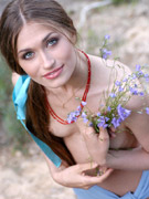 Loose shiela with a sheer blue wrap models nude under a tree.